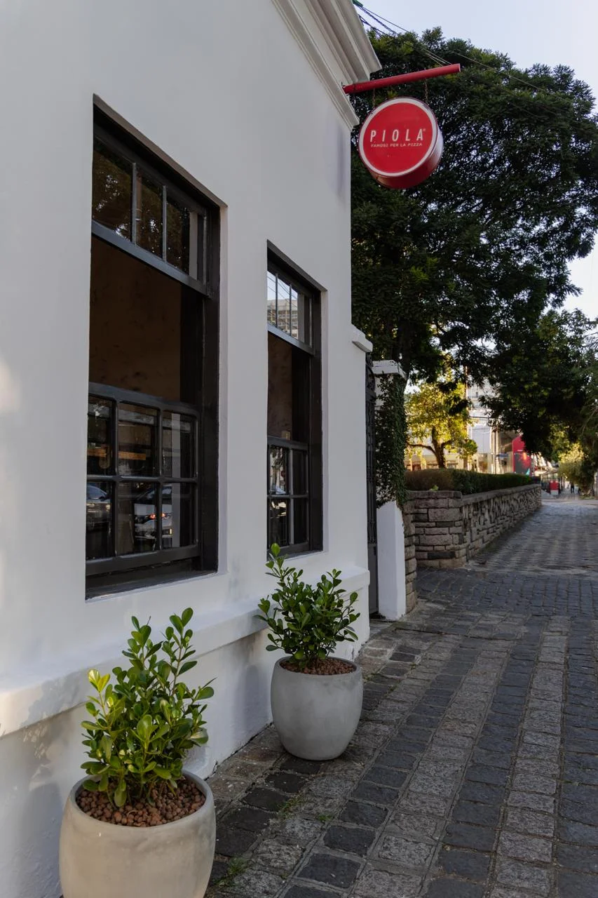 Fachada frontal da Piola na região de Batel com placa redonda vermelha