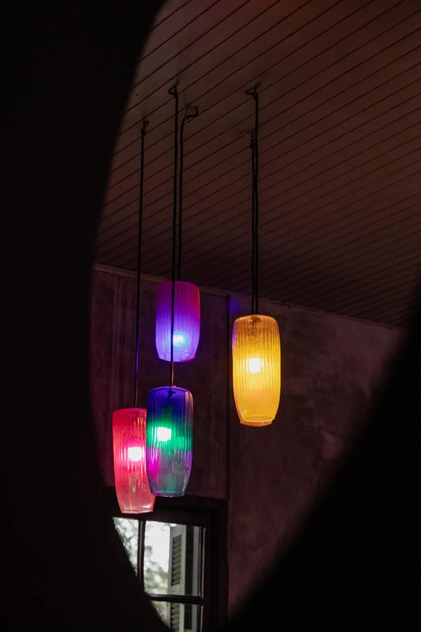 Detalhes das luminárias coloridas em tons rosa, roxo e amarelo