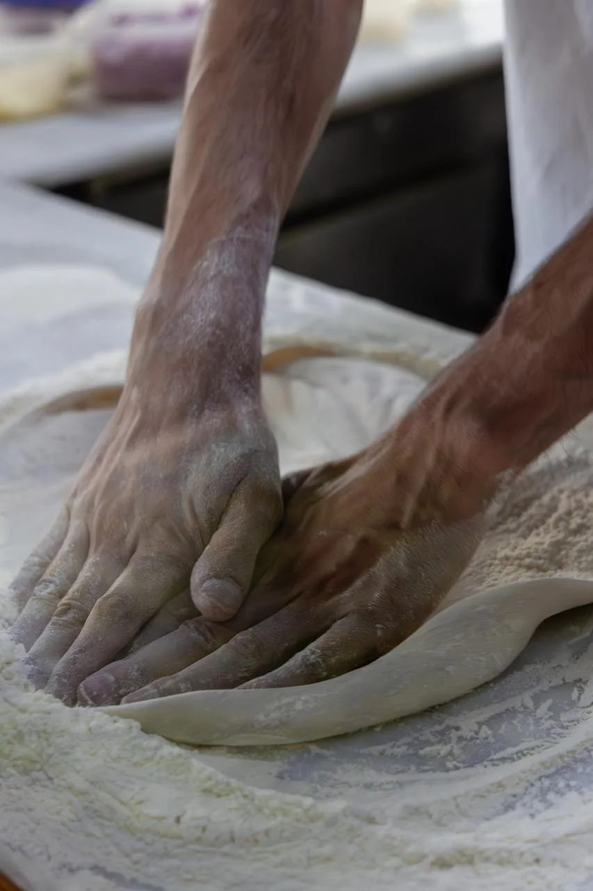Mãos de pizzaiolo amassando massa de pizza fresca